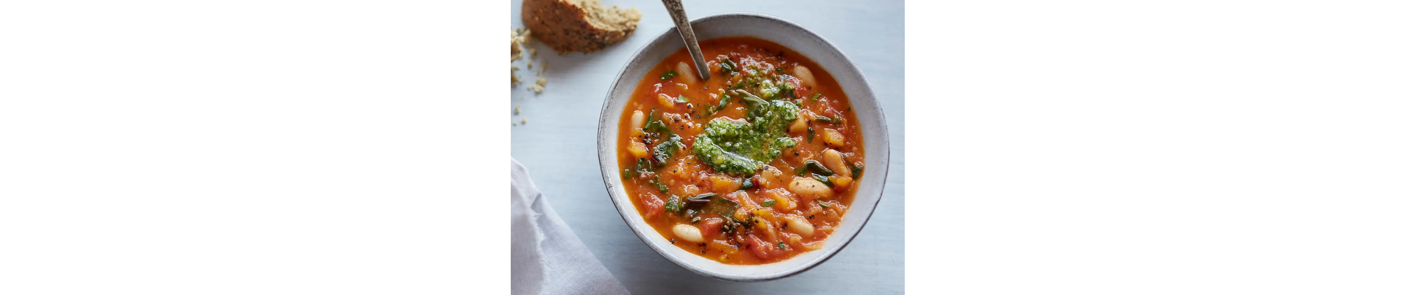 Tuscan bean and pumpkin soup with parsley pesto in bowl with spoon