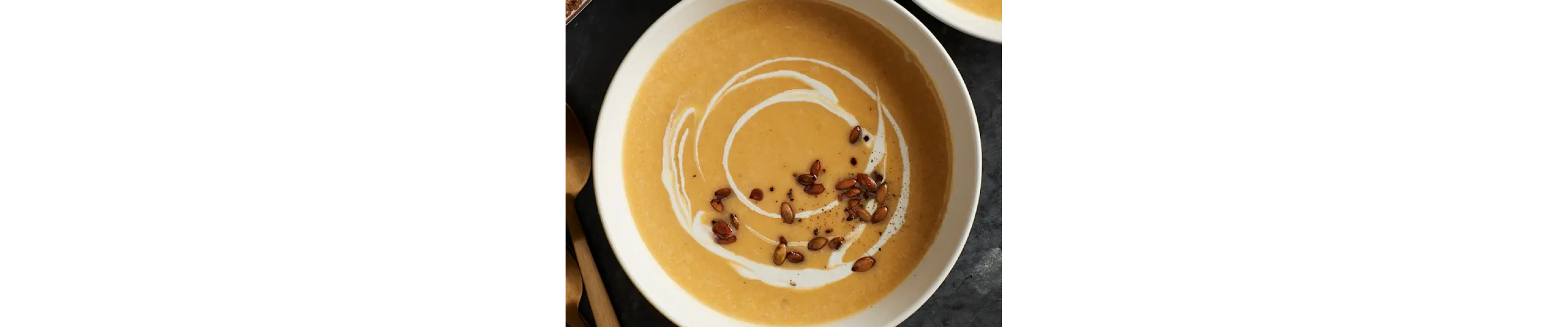 Bowl of pumpkin soup garnished with toasted pepitas