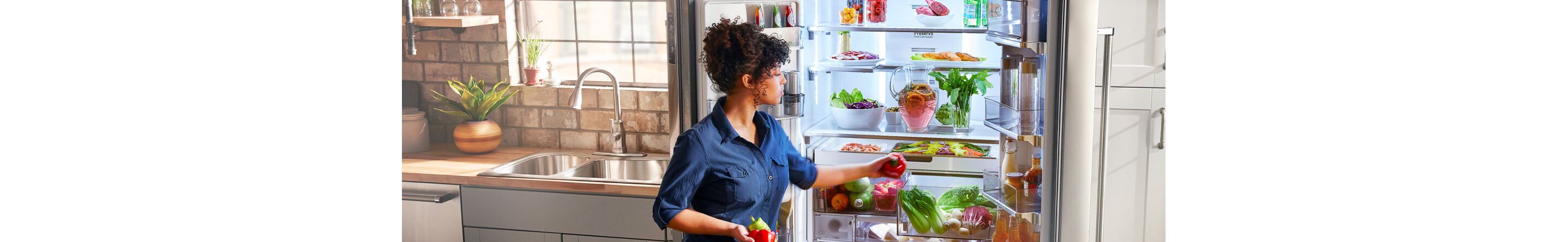Person loading bell peppers into the crisper drawer of a refrigerator