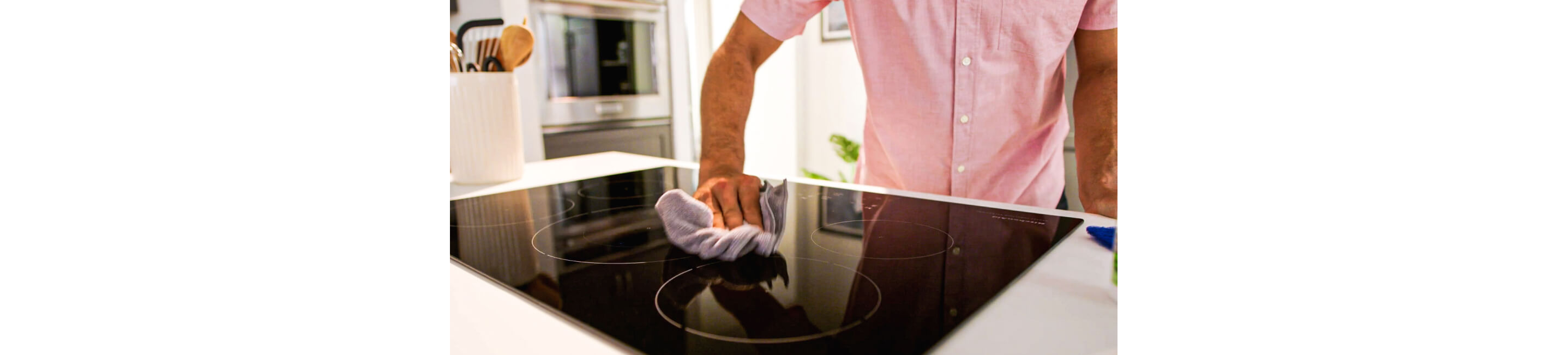 A person cleaning an induction cooktop.