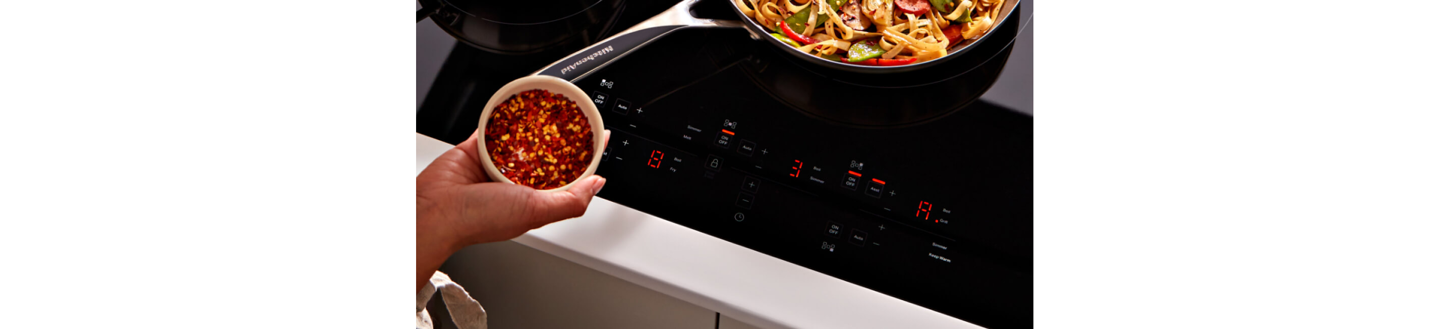 A person seasoning food at an induction cooktop.