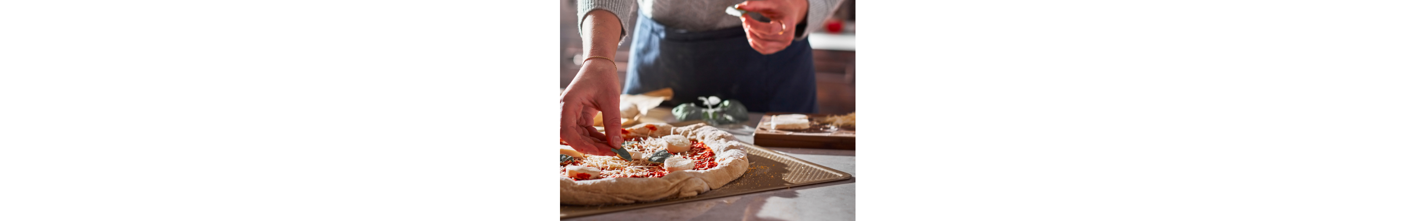 Person adding toppings to a pizza