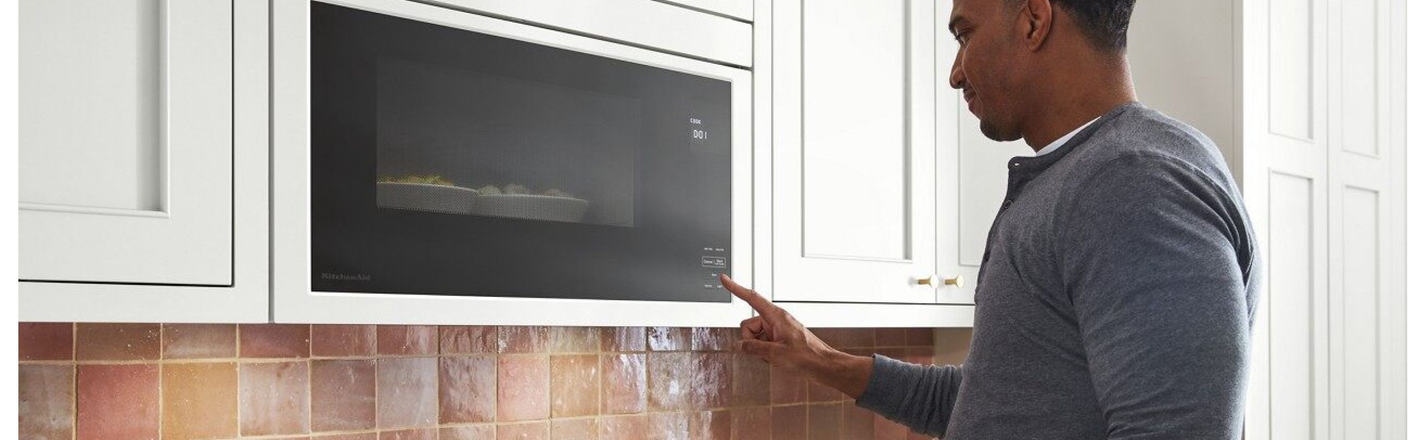 A Finger pressing a start button on a microwave