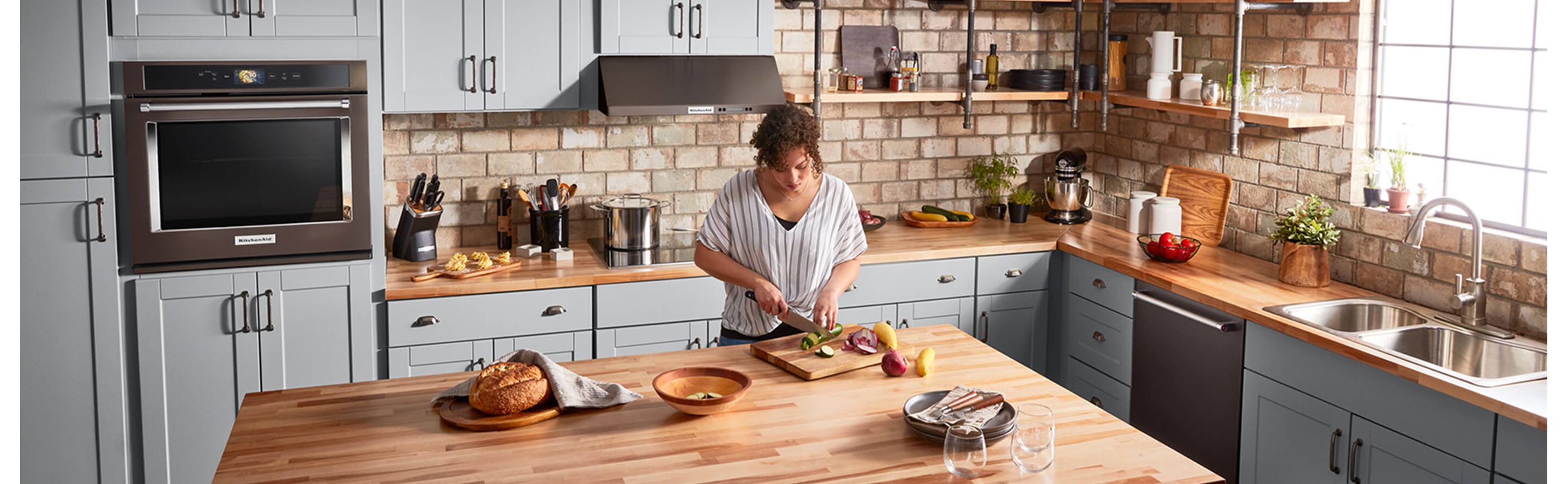 A person chopping vegetables at an island in a large, spacious kitchen