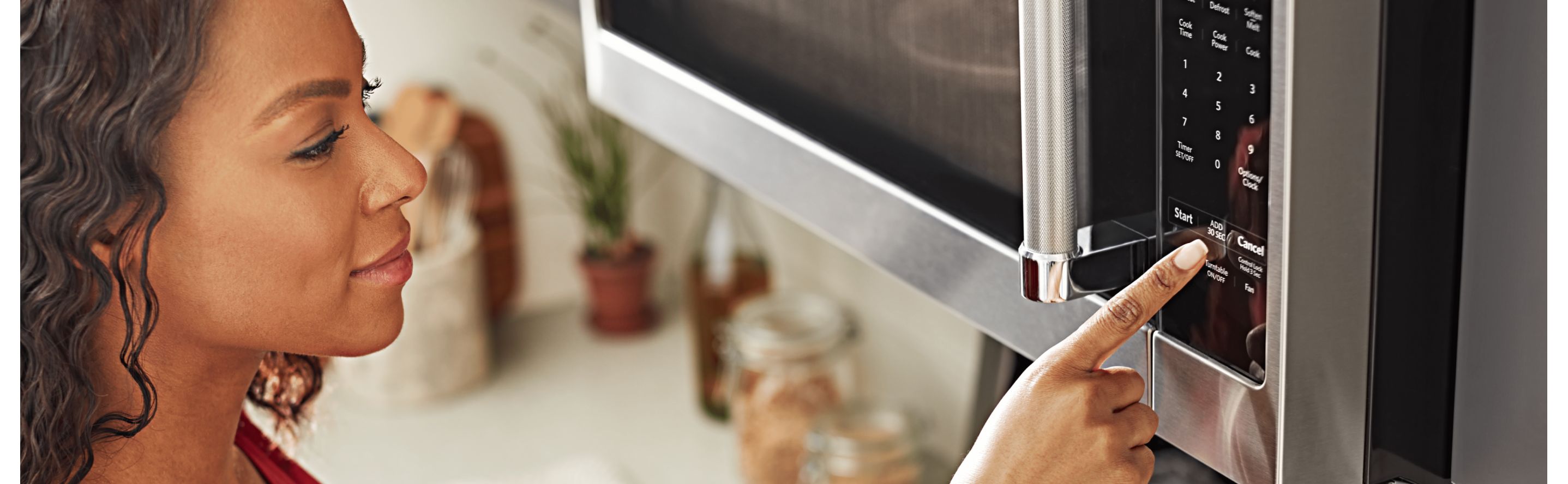 A person selecting a microwave setting on an over-the-range KitchenAid® microwave.