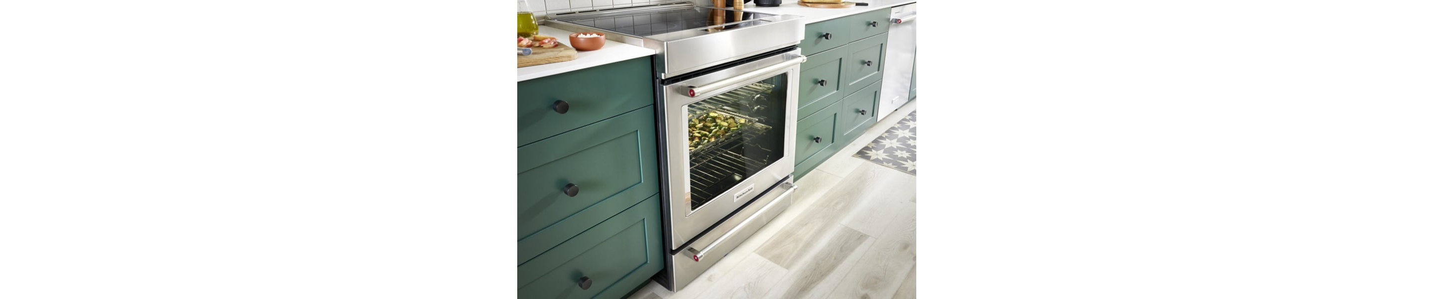 Stainless steel KitchenAid® induction range in a kitchen with green cabinets