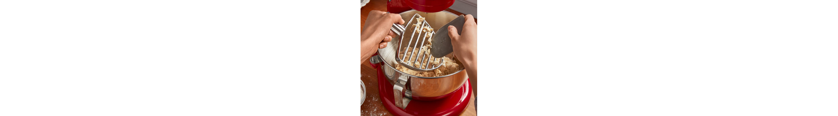 Person scraping dough off of pastry beater into stand mixer