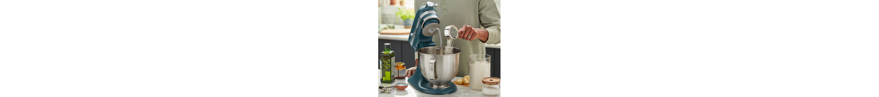 Person adding ingredients to a stand mixer bowl