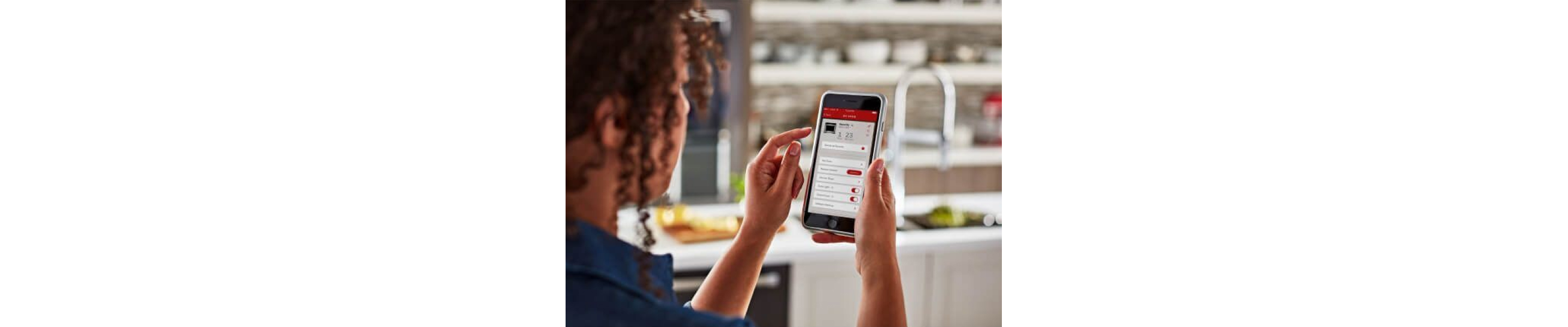A woman using the KitchenAid® smart appliance app on a mobile device