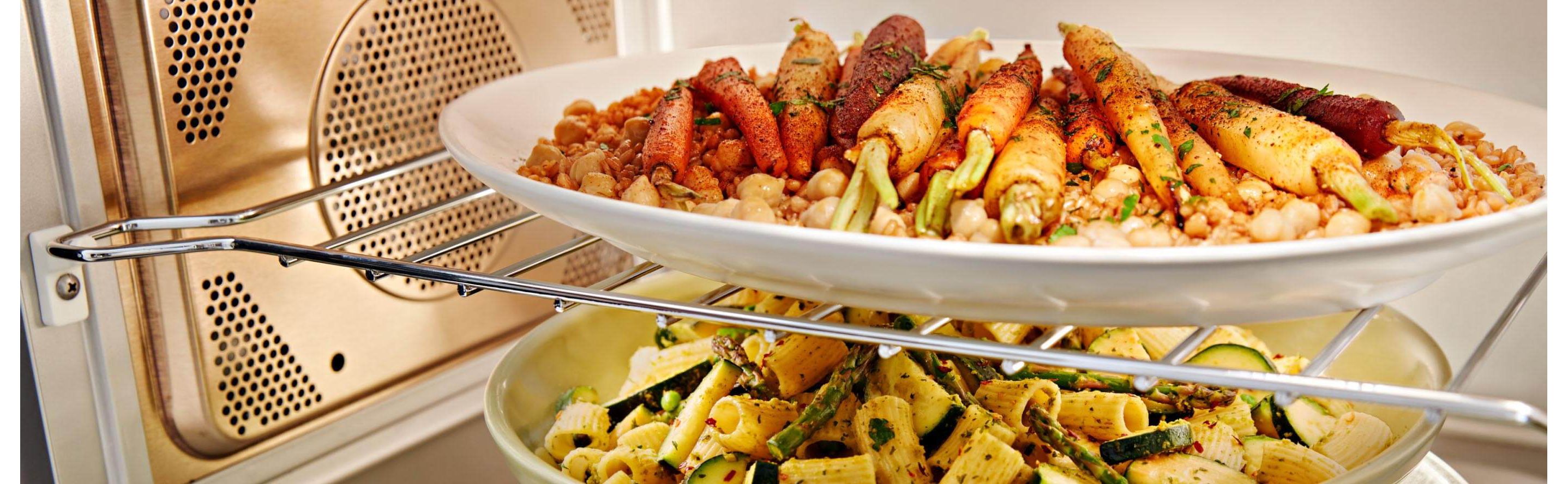 Two plates of food cooking inside a convection microwave
