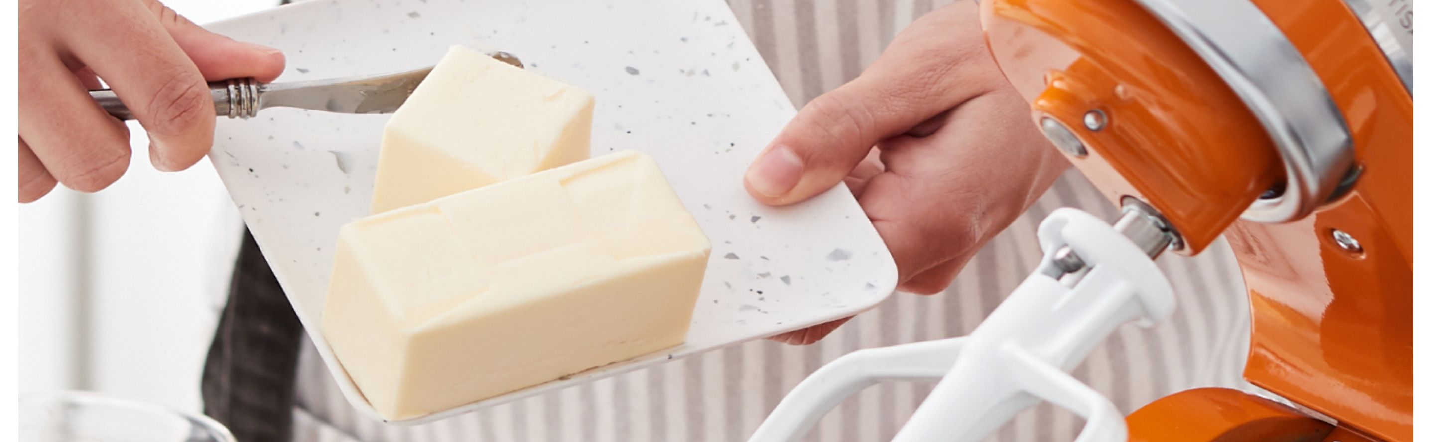 A person putting shortening in a stand mixer bowl