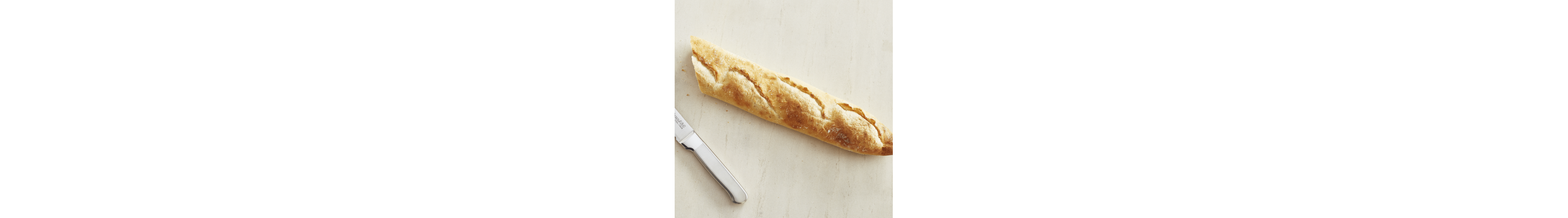 Fresh baguette next to a kitchen knife