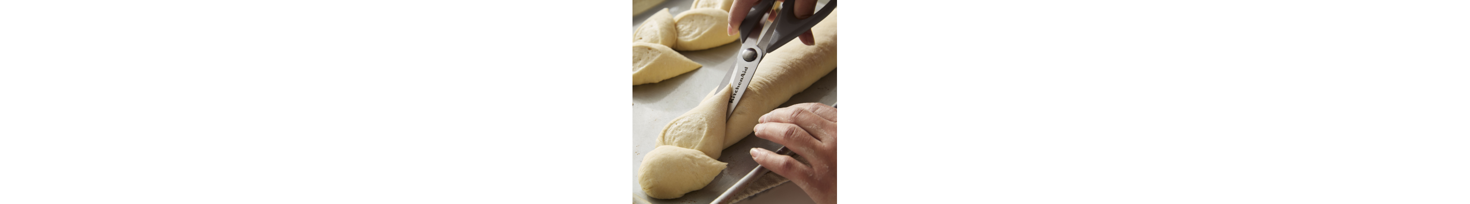 Person cutting bread dough with scissors
