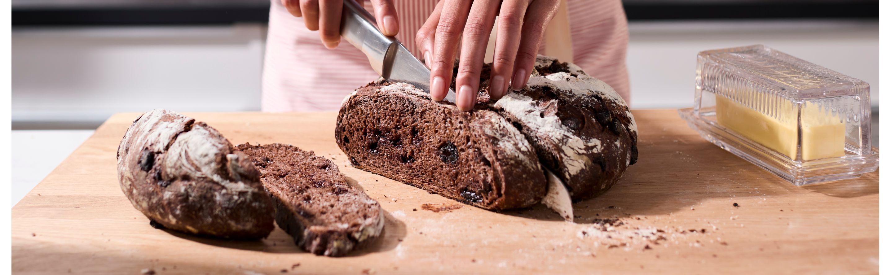 Person slicing dark brown bread