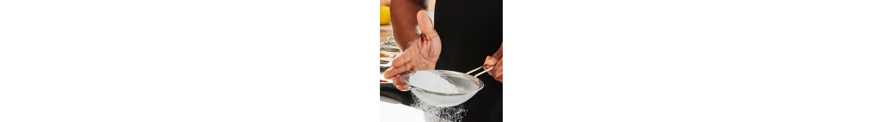 Person sifting sugar into a recipe