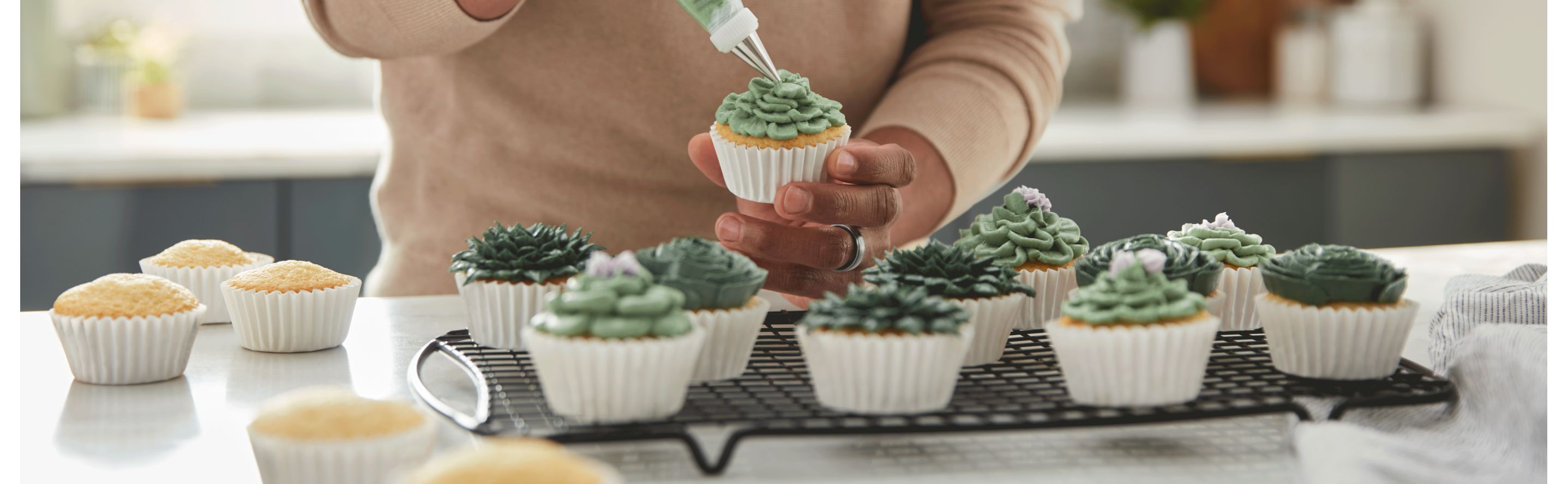 Person piping frosting onto a cupcake