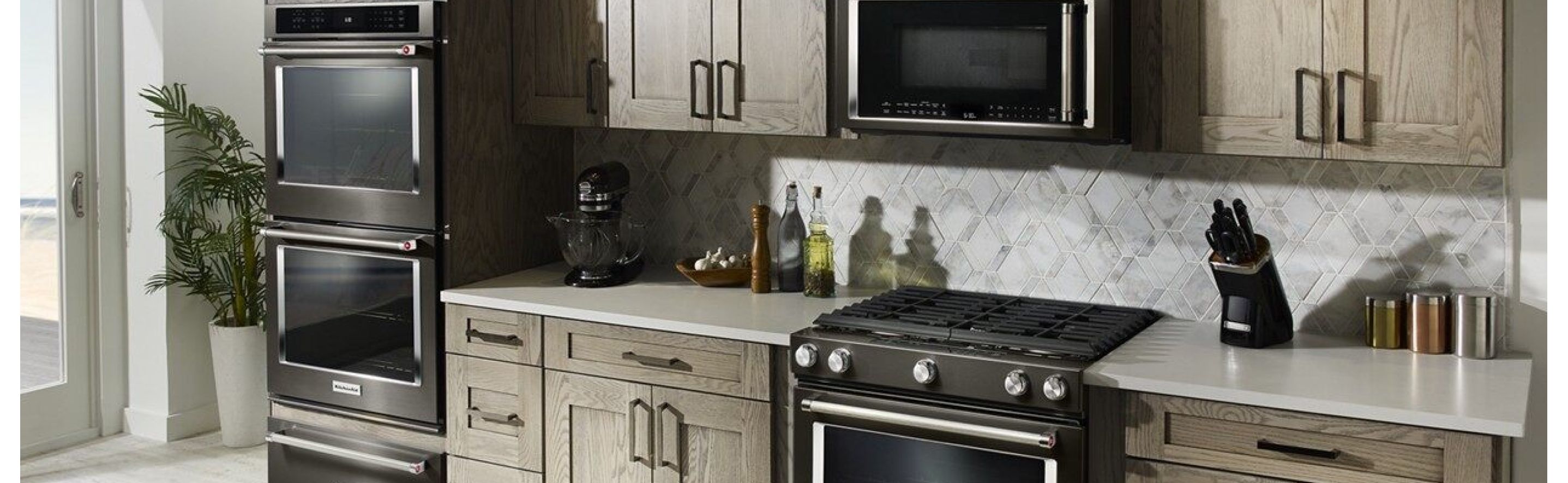 A black range, wall oven, microwave and warming drawer in a kitchen.