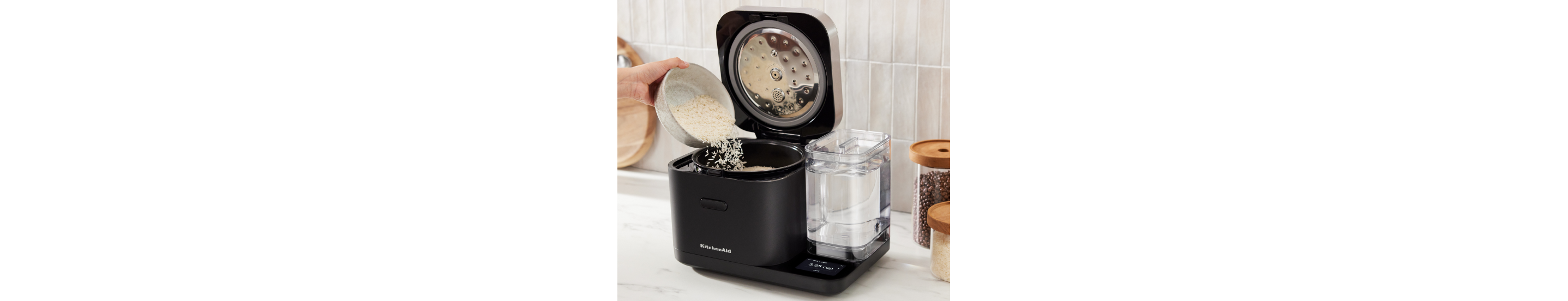 An open Grain and Rice Cooker with a person pouring rice into it.