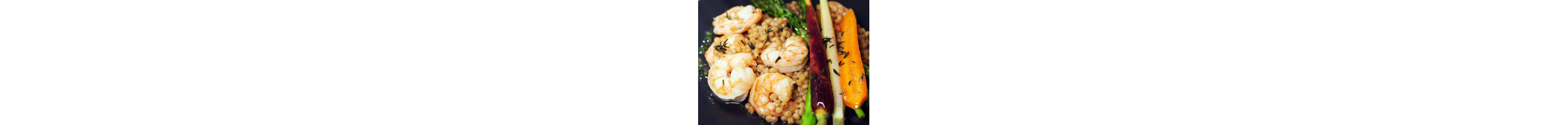 A plate of steamed shrimp served with couscous, asparagus and heirloom carrots.