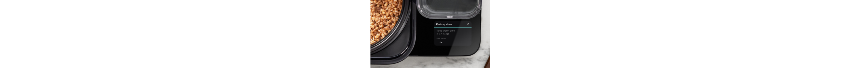 A close up of the touchscreen's keep warm function, with cooked grains in the pot of the Grain and Rice Cooker.