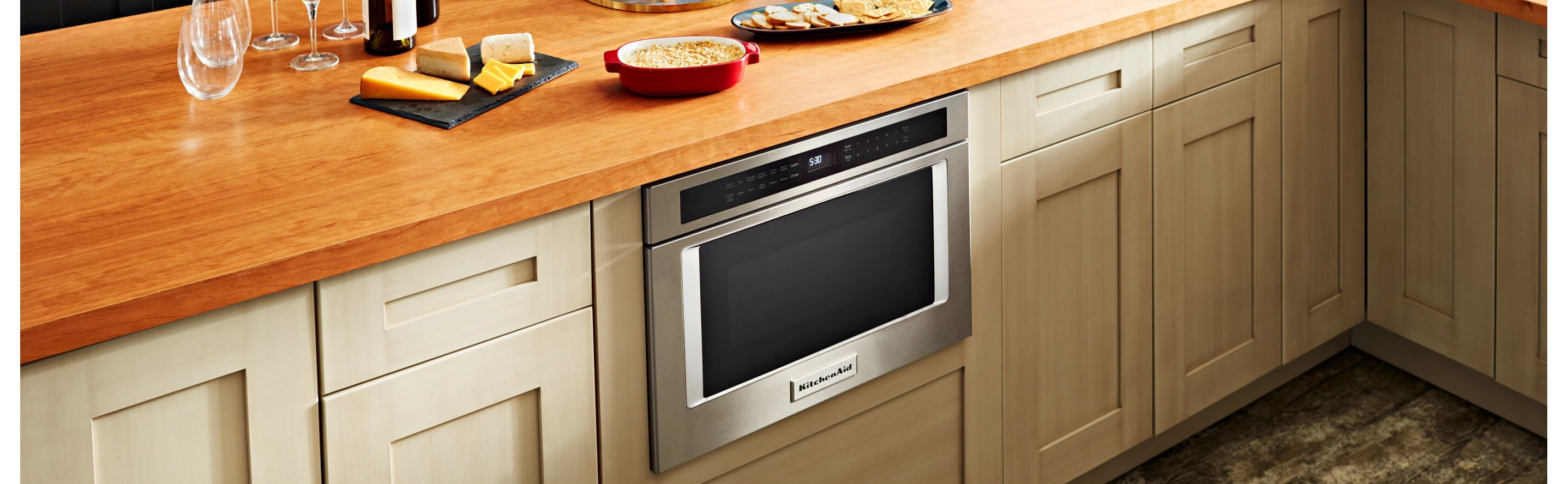 A KitchenAid® microwave drawer below a counter with various food items
