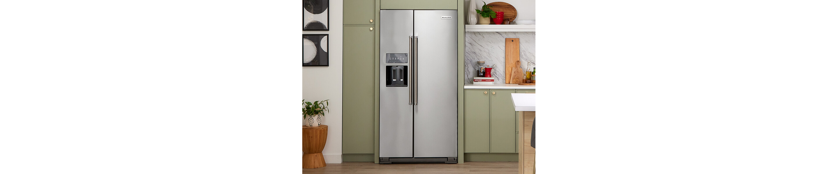 A KitchenAid® side-by-side refrigerator within muted green cabinets
