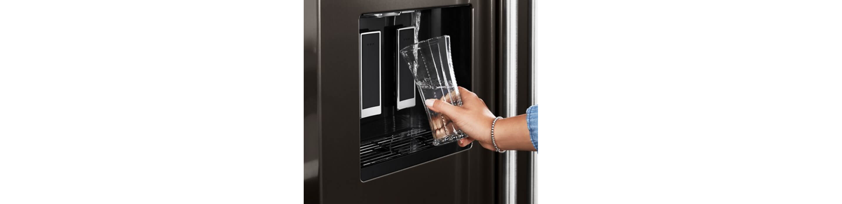 A person filling water from an external dispenser of the KitchenAid® French Door Bottom Mount Refrigerator.