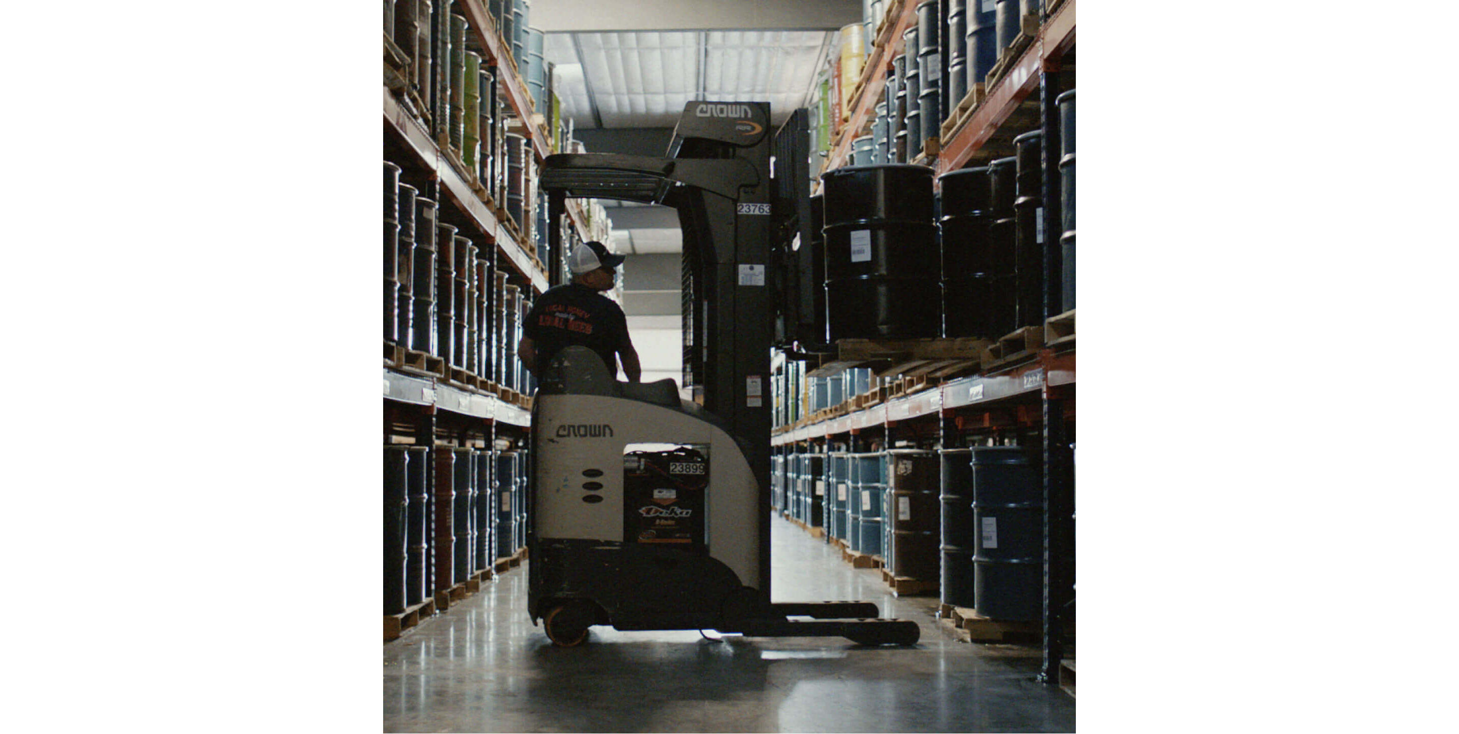 A man operating a forklift carrying barrels of honey.