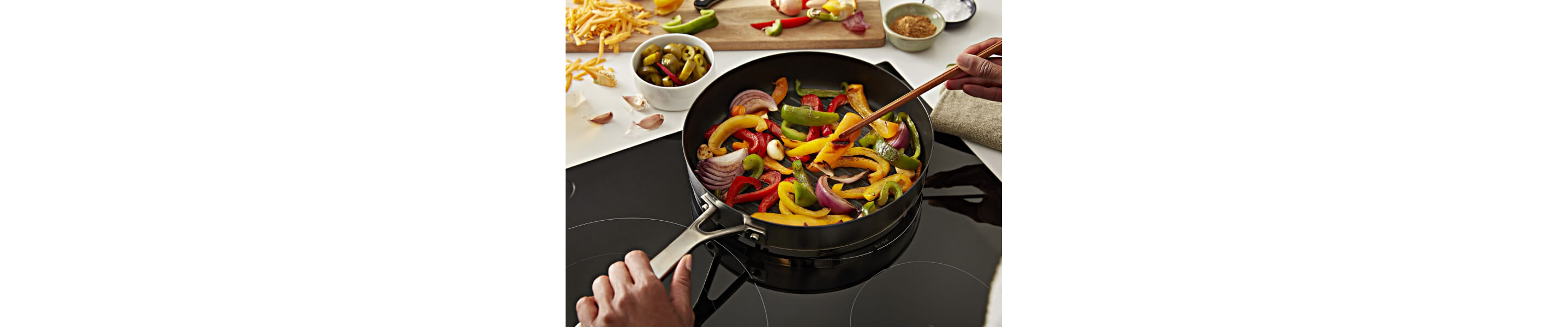 Person stirring vegetables in a pan on a cooktop