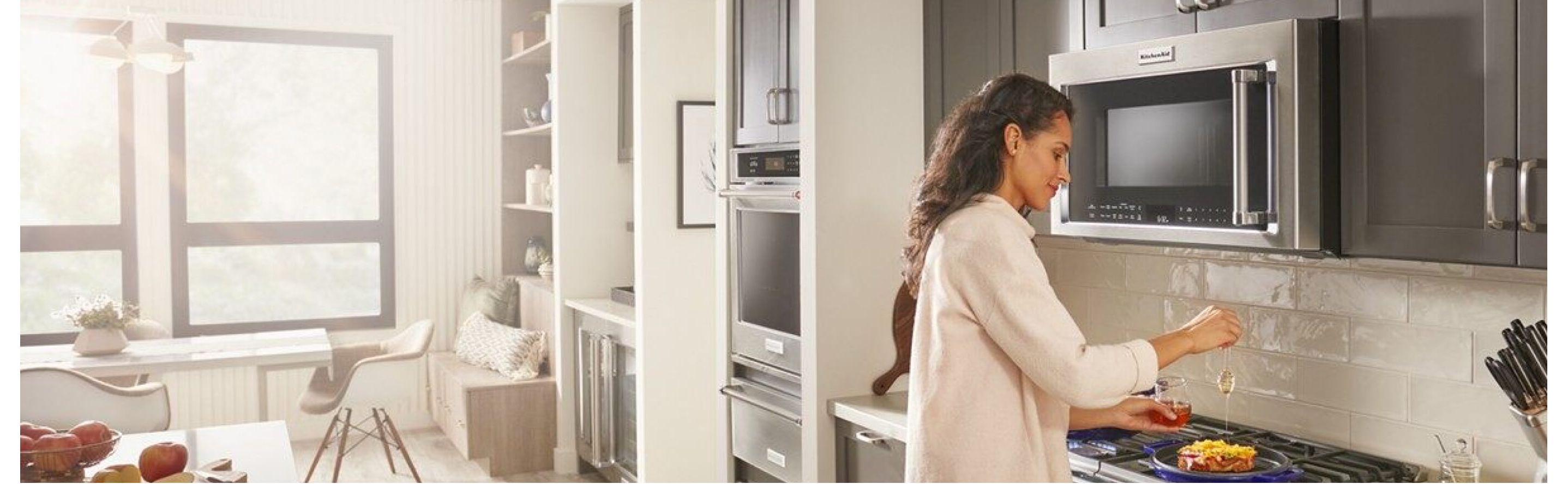  Person cooking on a stovetop with a KitchenAid® over-the-range microwave above
